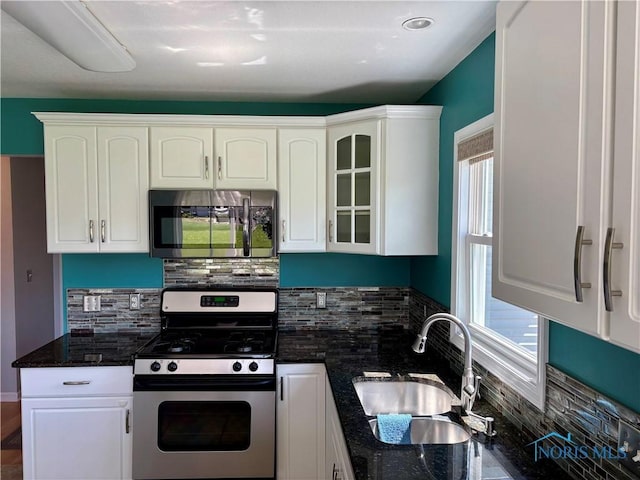 kitchen with a sink, white cabinetry, appliances with stainless steel finishes, and tasteful backsplash