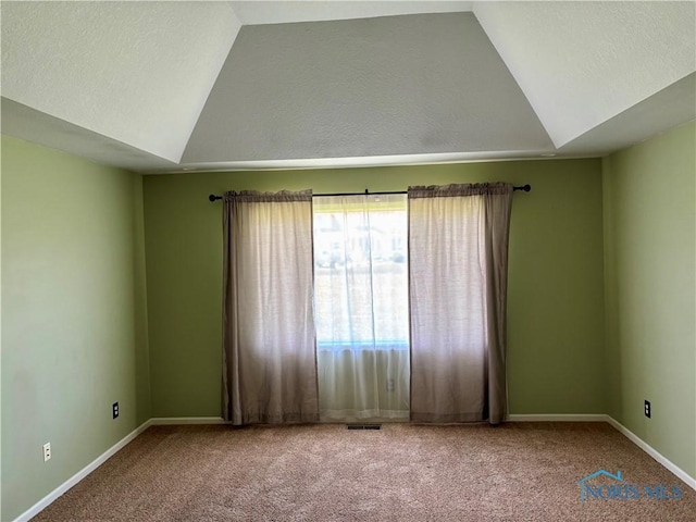 carpeted spare room with baseboards and vaulted ceiling