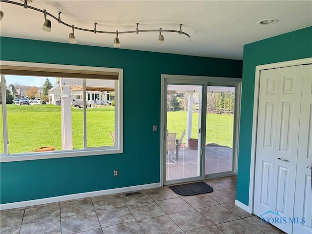 doorway with baseboards, visible vents, and tile patterned flooring