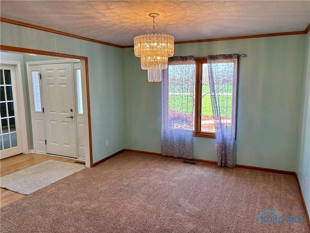 entrance foyer featuring an inviting chandelier, carpet, crown molding, and visible vents