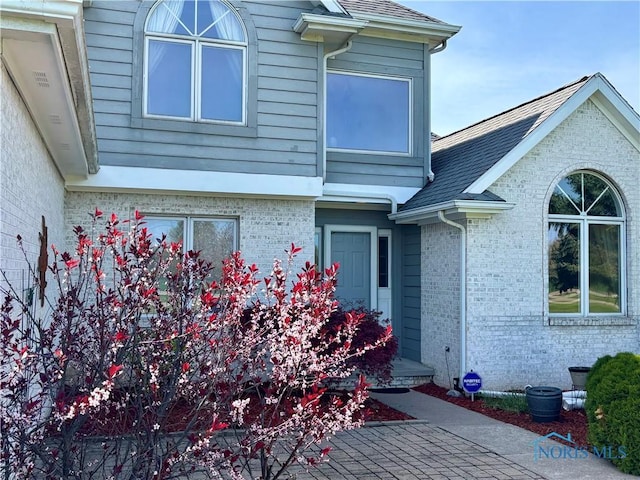 property entrance with brick siding and roof with shingles