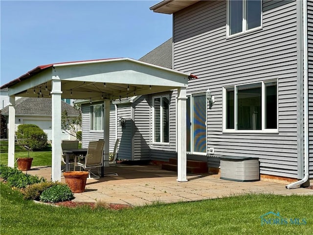 back of property with entry steps, a patio, and a lawn