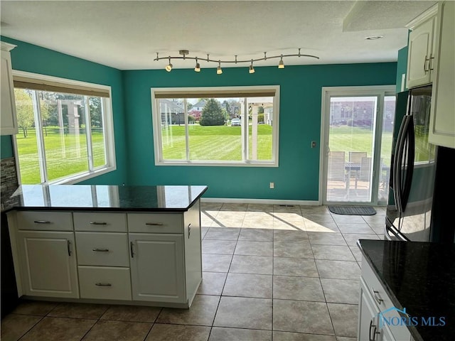 kitchen featuring freestanding refrigerator, baseboards, tile patterned floors, and white cabinets