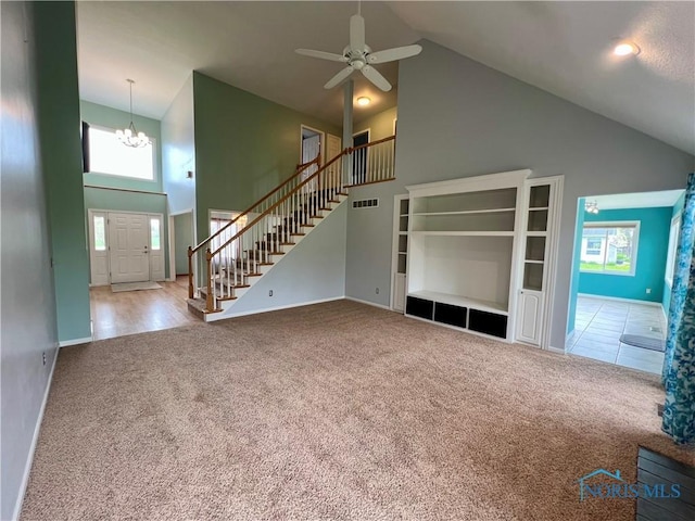 unfurnished living room featuring carpet floors, stairs, a healthy amount of sunlight, and high vaulted ceiling