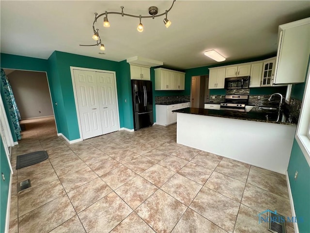 kitchen with visible vents, light tile patterned flooring, dark countertops, a sink, and appliances with stainless steel finishes