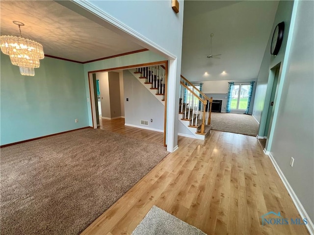 unfurnished living room with baseboards, visible vents, stairway, and ceiling fan with notable chandelier
