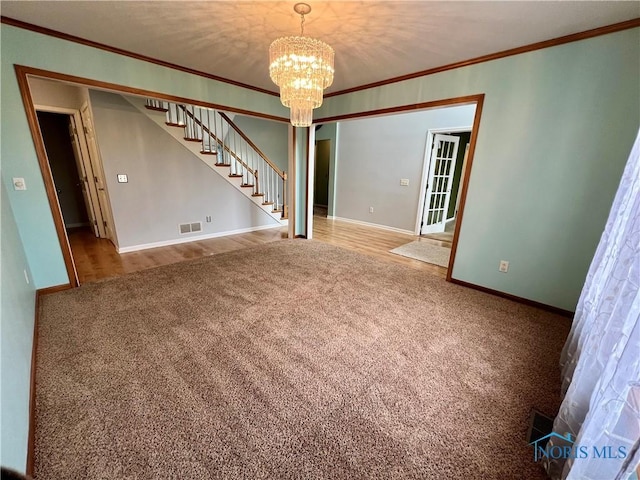 spare room featuring carpet flooring, a notable chandelier, stairway, and ornamental molding