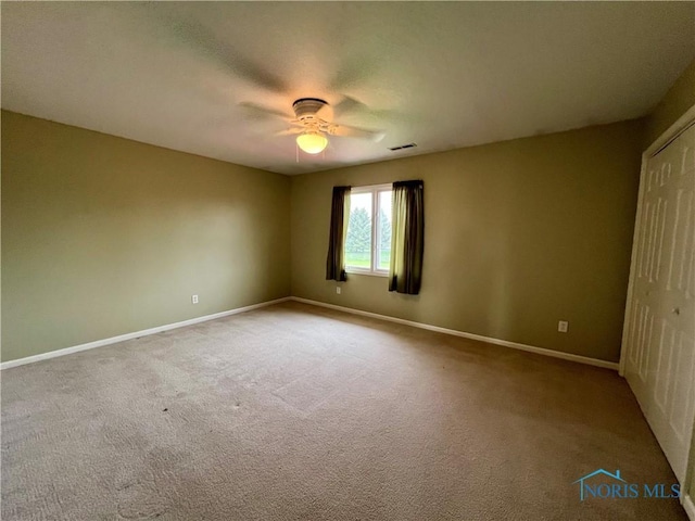 carpeted empty room featuring a ceiling fan, baseboards, and visible vents
