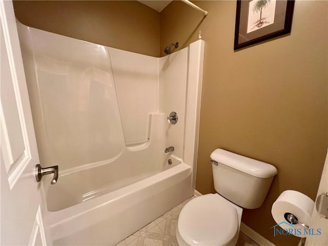 bathroom with baseboards, washtub / shower combination, and toilet