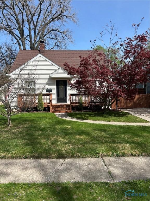 view of front of house with a front lawn, a wooden deck, a chimney, and fence