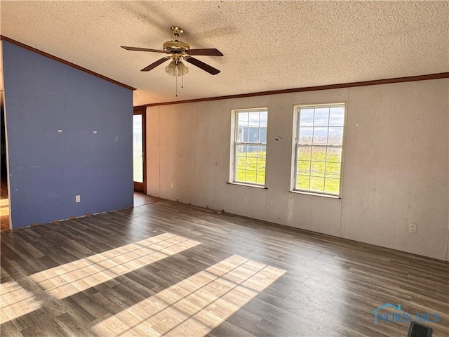 spare room with visible vents, ornamental molding, wood finished floors, a textured ceiling, and a ceiling fan