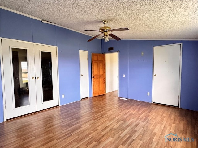unfurnished bedroom with a textured ceiling, visible vents, french doors, and wood finished floors