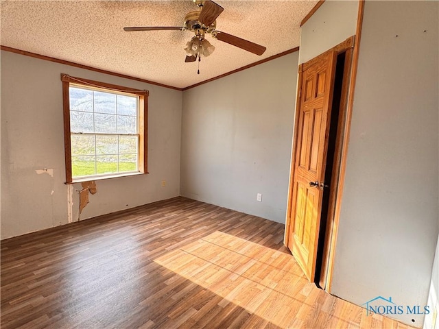 spare room featuring crown molding, a textured ceiling, ceiling fan, and wood finished floors
