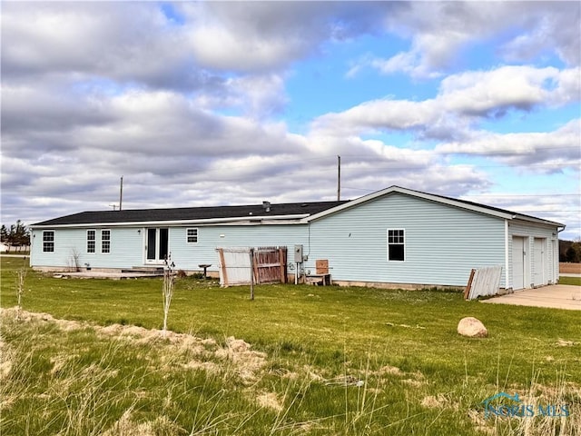 back of house featuring a lawn, entry steps, and a garage