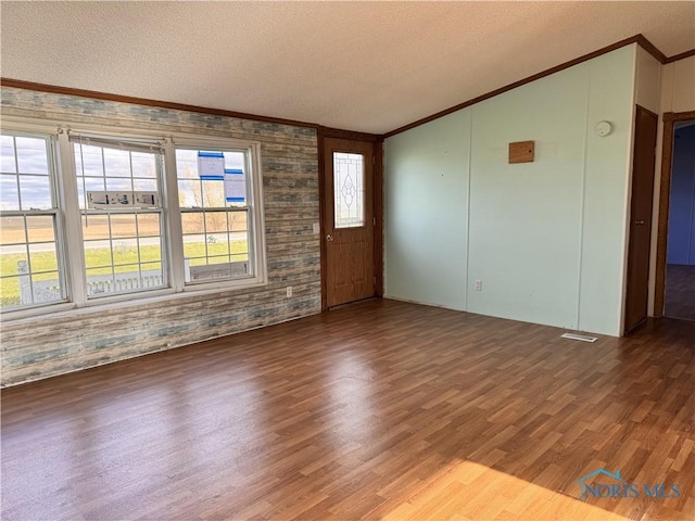 spare room featuring crown molding, vaulted ceiling, and wood finished floors