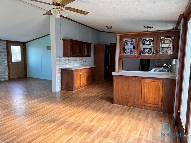 kitchen featuring ceiling fan, vaulted ceiling, light countertops, light wood-style floors, and ornamental molding