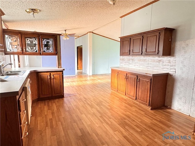 kitchen featuring ceiling fan, light wood-type flooring, light countertops, a textured ceiling, and a sink