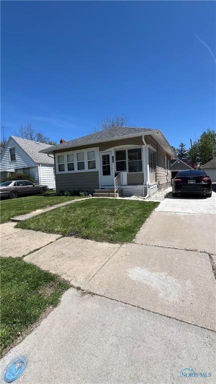 bungalow-style house with entry steps, driveway, and a front lawn