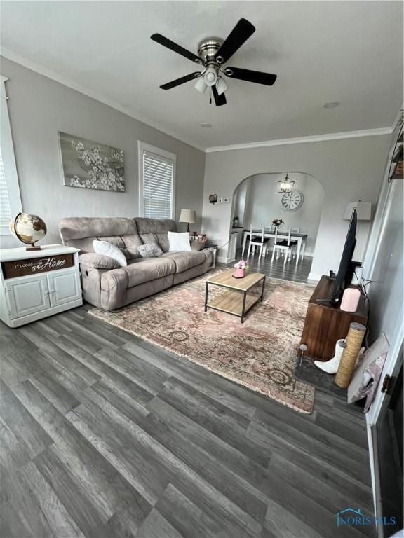 living room featuring arched walkways, ornamental molding, a ceiling fan, and wood finished floors