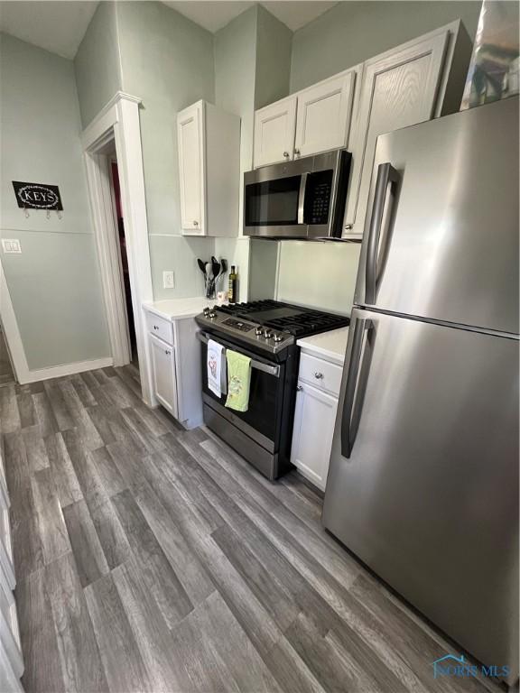 kitchen with light countertops, stainless steel appliances, and dark wood-style floors