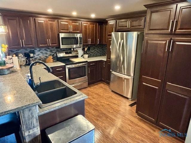 kitchen featuring a sink, stainless steel appliances, light wood-type flooring, and dark brown cabinets