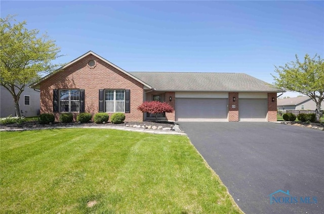 ranch-style home with brick siding, an attached garage, a front yard, and aphalt driveway