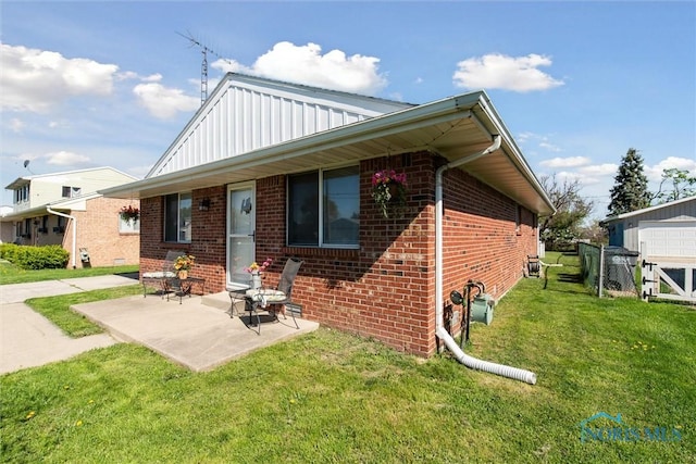 2123 Keen Ave, Toledo, OH 43611 - rear view of property featuring a lawn, brick siding, board and batten siding, and a patio area