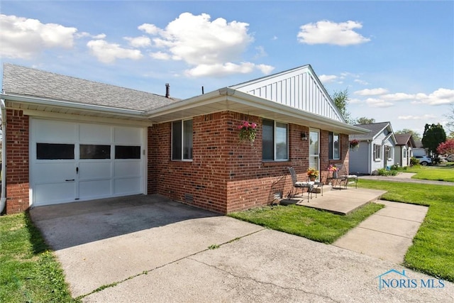 2123 Keen Ave, Toledo, OH 43611 - view of front facade featuring board and batten siding, an attached garage, driveway, and brick siding