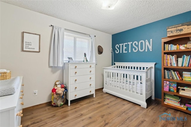 2123 Keen Ave, Toledo, OH 43611 - bedroom featuring a textured ceiling, wood finished floors, and a crib
