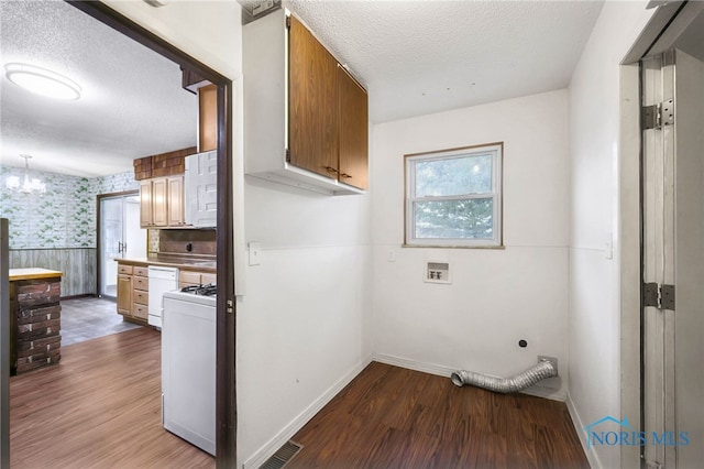 13921 Defiance Pike, Rudolph, OH 43462 - laundry area featuring baseboards, wood finished floors, wallpapered walls, a textured ceiling, and cabinet space