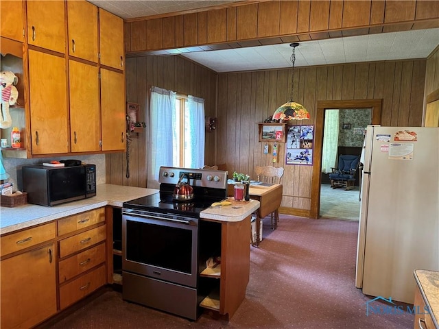 kitchen featuring freestanding refrigerator, wood walls, black microwave, light countertops, and stainless steel electric range