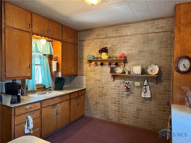 kitchen with a sink, light countertops, open shelves, and brown cabinets