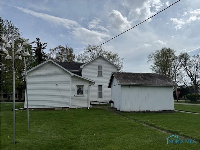 rear view of property with an outdoor structure and a yard