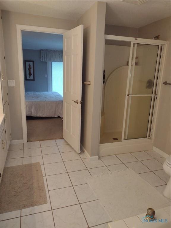 ensuite bathroom featuring tile patterned floors, baseboards, and a stall shower
