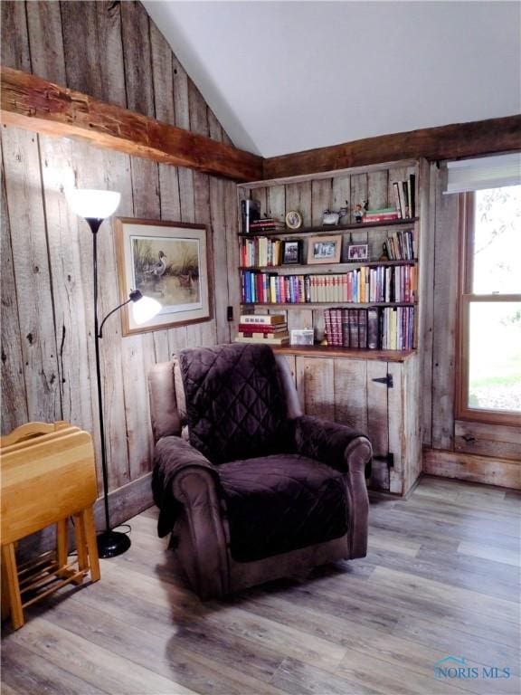 sitting room featuring wood walls, wood finished floors, and vaulted ceiling