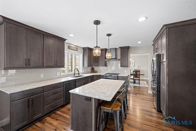 1135 Pimlico Park, Holland, OH 43528 - kitchen featuring wall chimney range hood, dark brown cabinets, dark wood-style flooring, appliances with stainless steel finishes, and a kitchen island
