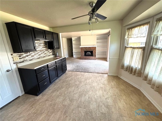kitchen with decorative backsplash, ceiling fan, light countertops, a textured ceiling, and dark cabinetry