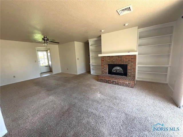 unfurnished living room featuring carpet flooring, ceiling fan, a fireplace, a textured ceiling, and visible vents
