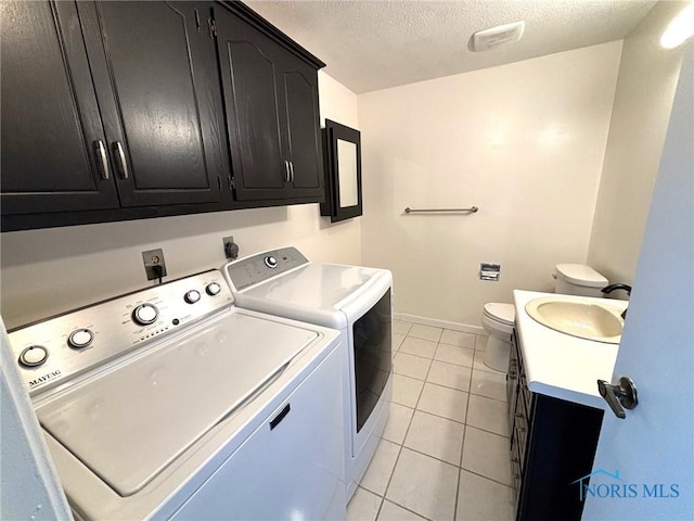 laundry area with a sink, separate washer and dryer, a textured ceiling, baseboards, and light tile patterned floors