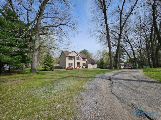 view of front of home with a front lawn and gravel driveway