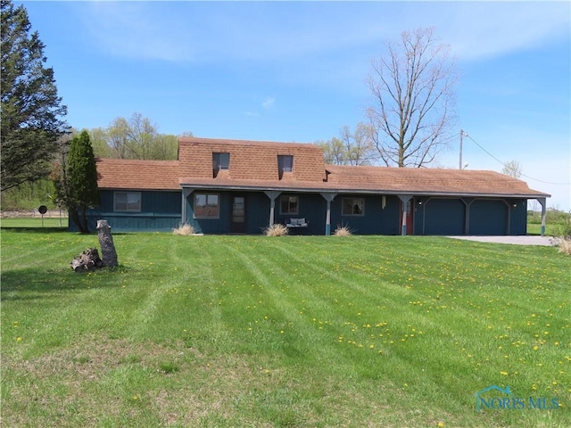 back of property with a garage, a yard, and driveway