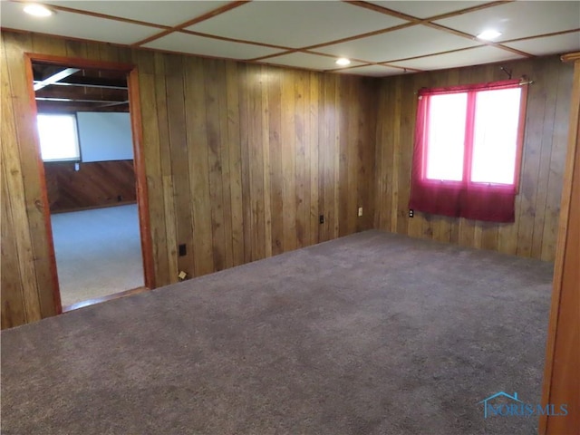 empty room with carpet floors, wood walls, and recessed lighting