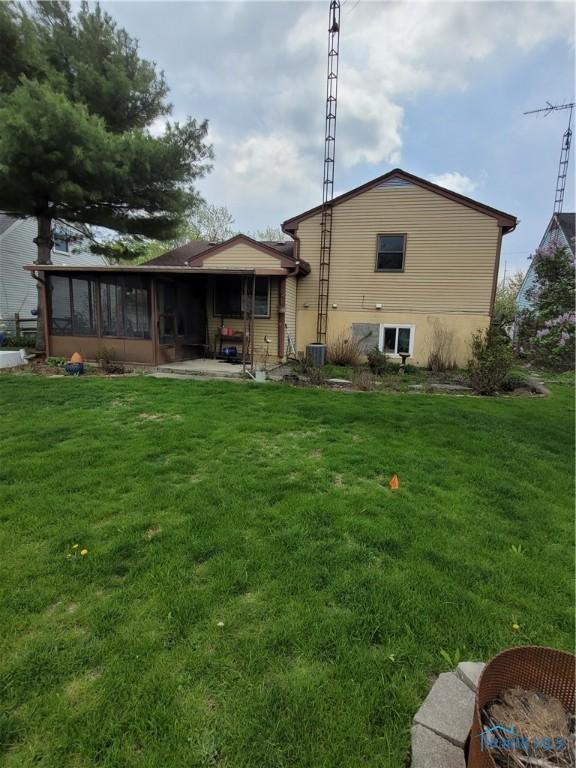 back of property with a lawn, central AC unit, and a sunroom