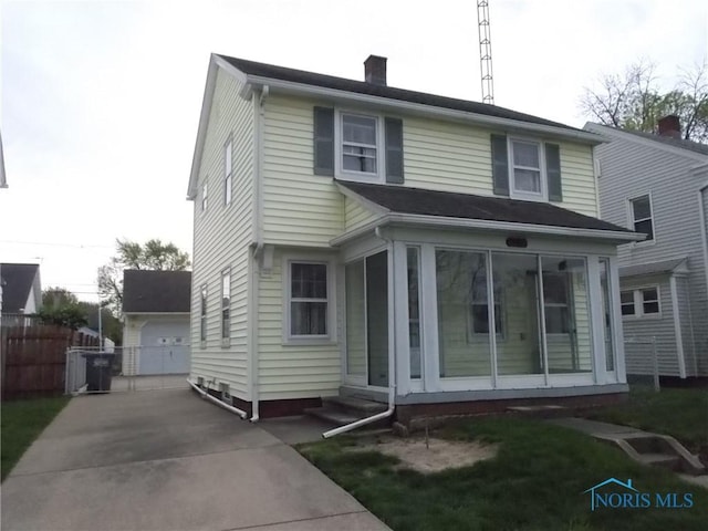 view of front of house featuring fence, a chimney, a sunroom, and a garage
