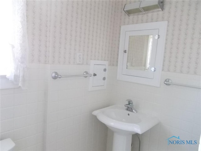 bathroom with tile walls, wainscoting, and wallpapered walls