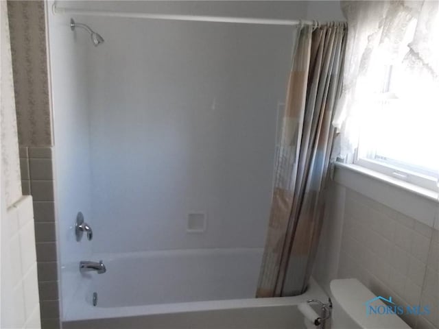 bathroom featuring shower / bathtub combination with curtain and toilet