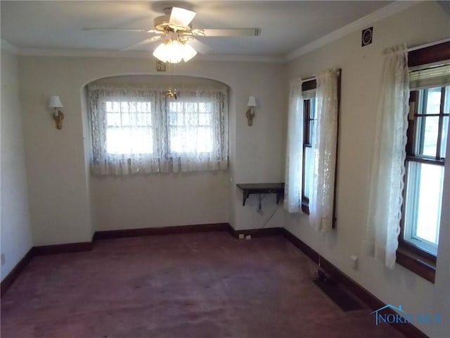 carpeted spare room featuring a healthy amount of sunlight, baseboards, ornamental molding, and a ceiling fan
