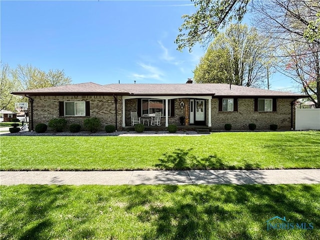 ranch-style house featuring covered porch, brick siding, and a front lawn