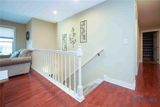 corridor featuring baseboards, recessed lighting, wood finished floors, and an upstairs landing