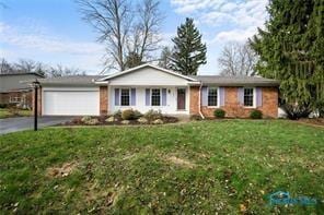 single story home with aphalt driveway, a front lawn, and a garage
